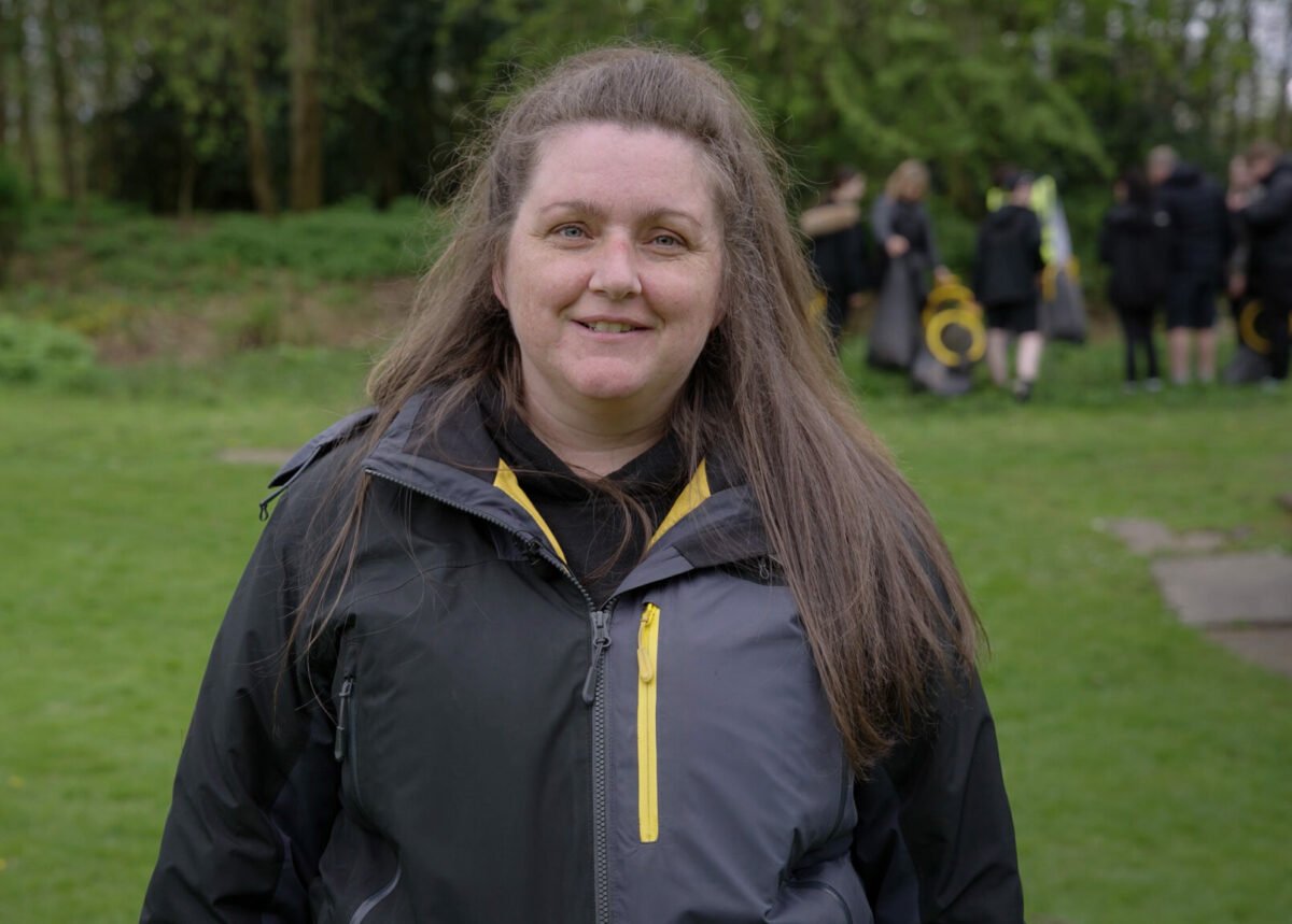 Michelle standing outdoors in a grassy field in front of a forest.