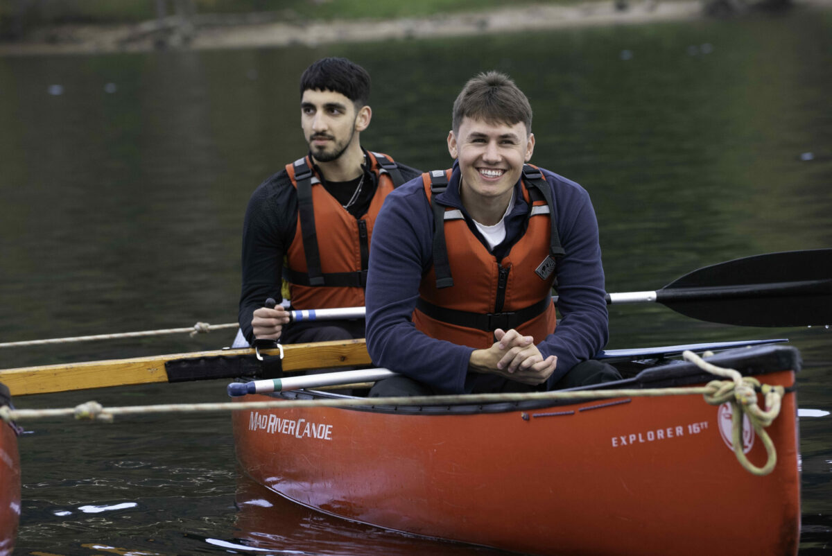 Two young people in a canoe wearing red lifejackets and smiling.