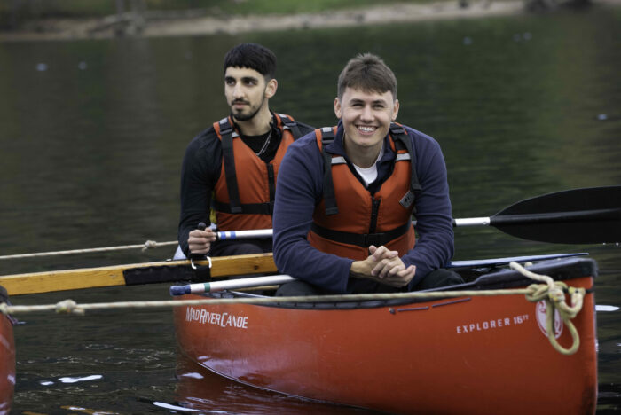 Two young people in a canoe wearing red lifejackets and smiling.