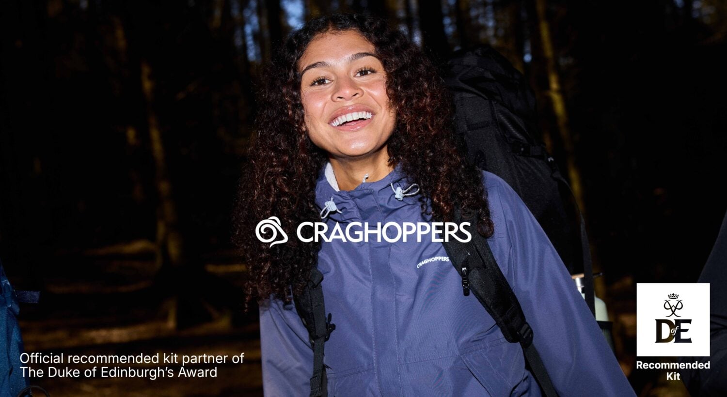 Person wearing a Craghoppers jacket and backpack on a woodland path, with Craghoppers logo and Duke of Edinburgh’s Award Recommended Kit badge.