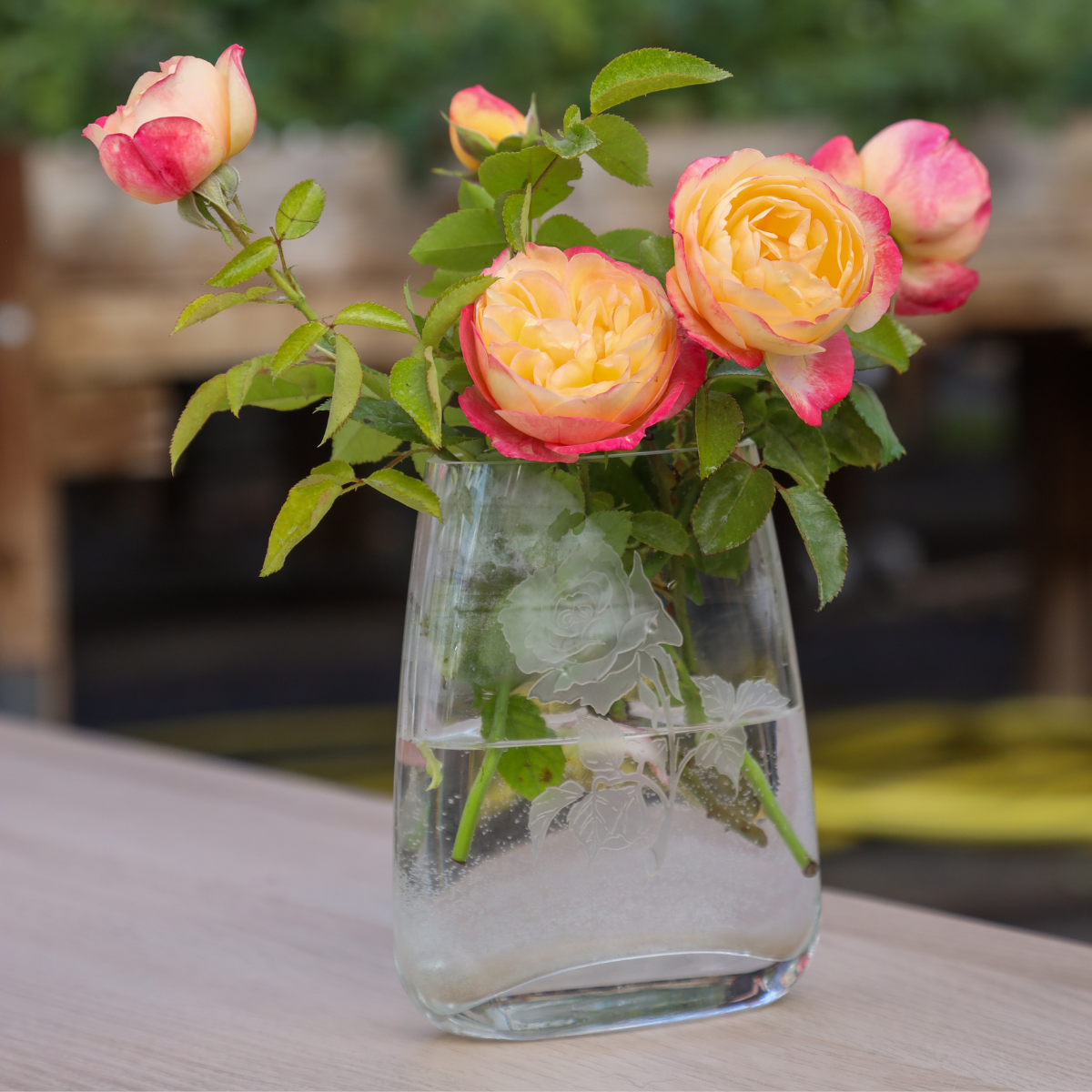 yellow and pink rose in a clear glass vase on a table