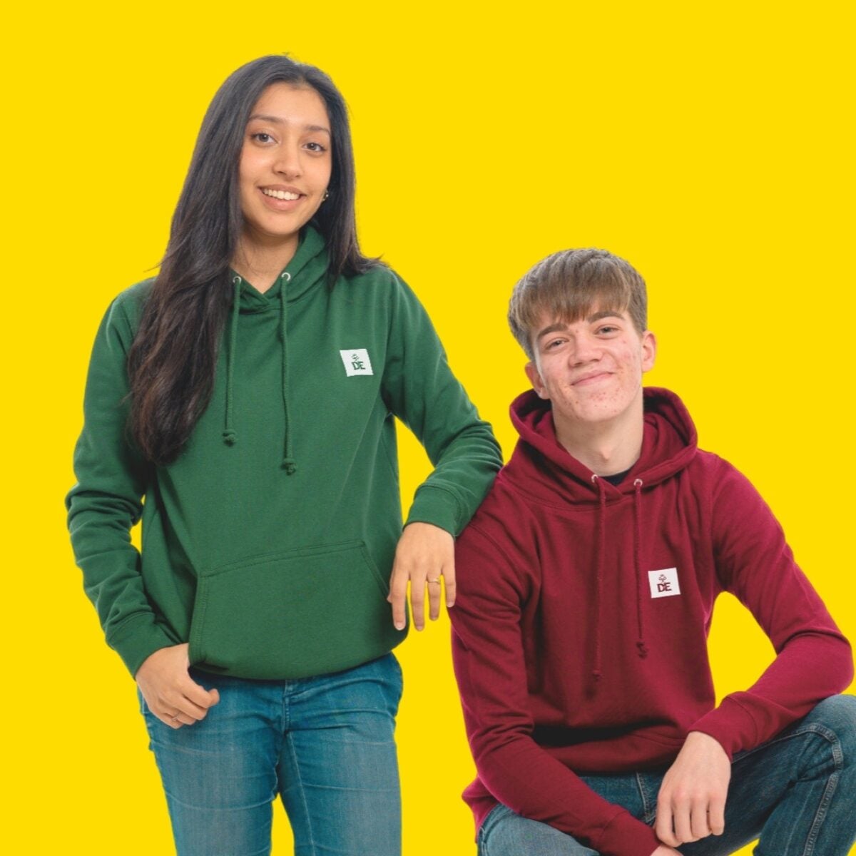 Two young people wearing DofE Hoodies in front of a yellow background