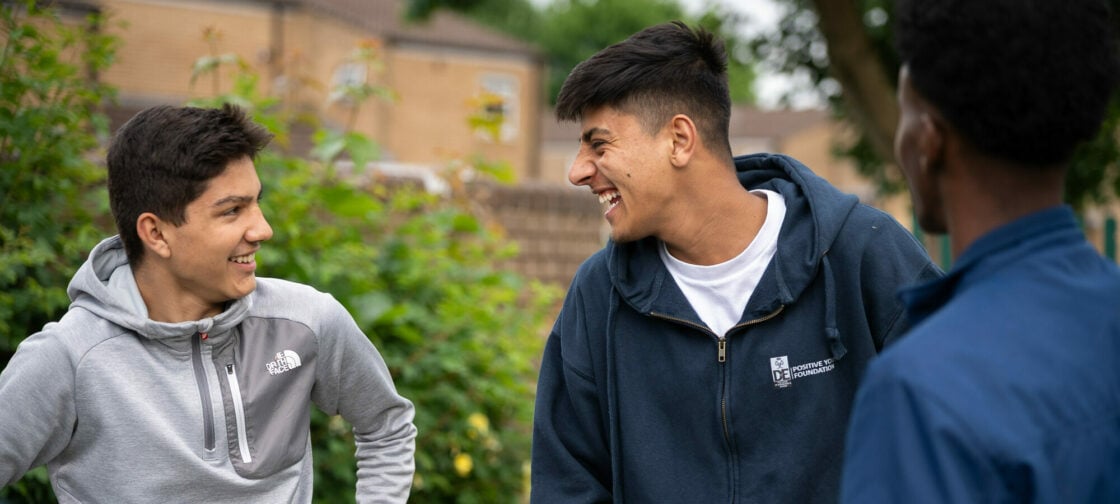 Two young people standing outside looking at each other and smiling.