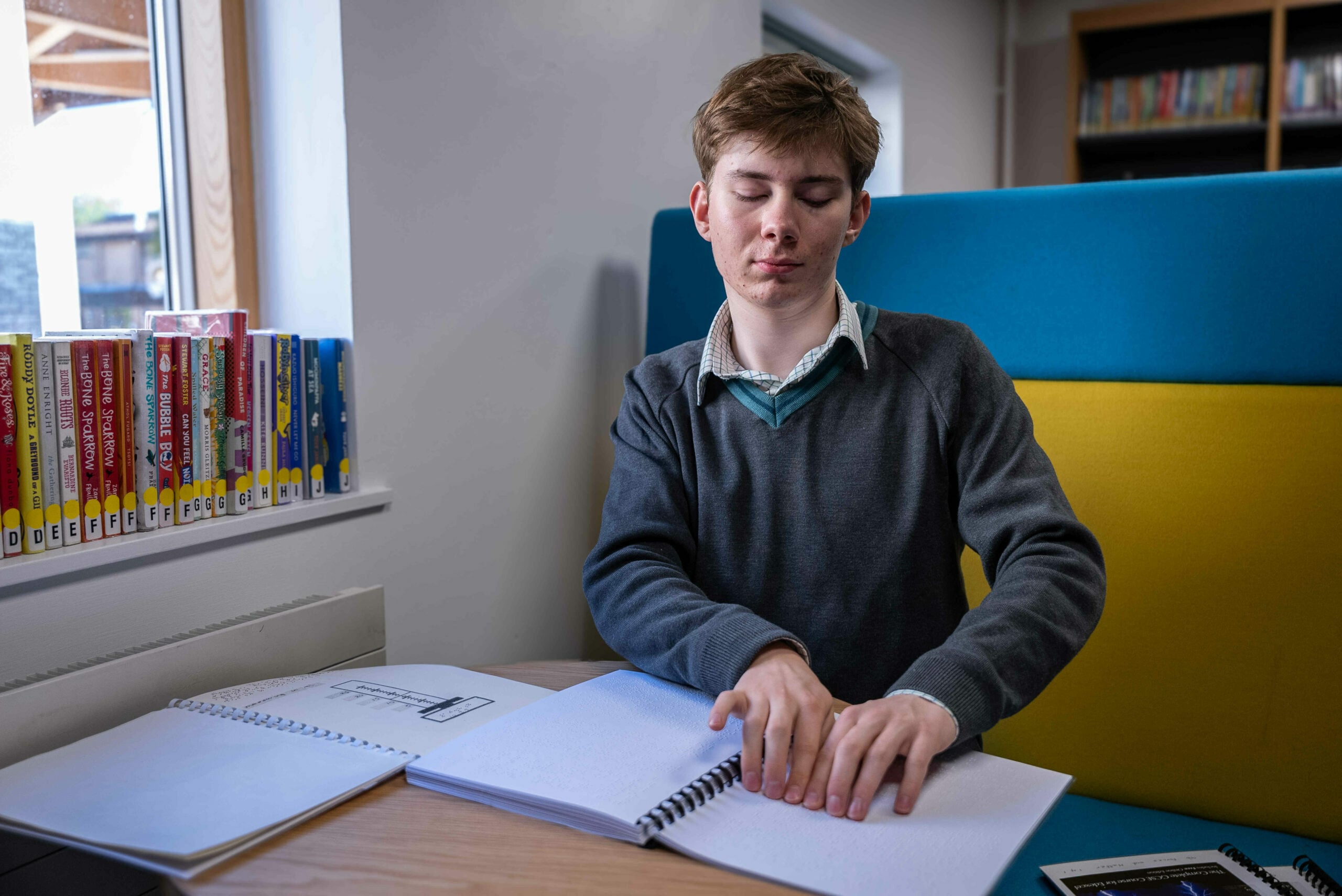 A young person reading a book in braille.