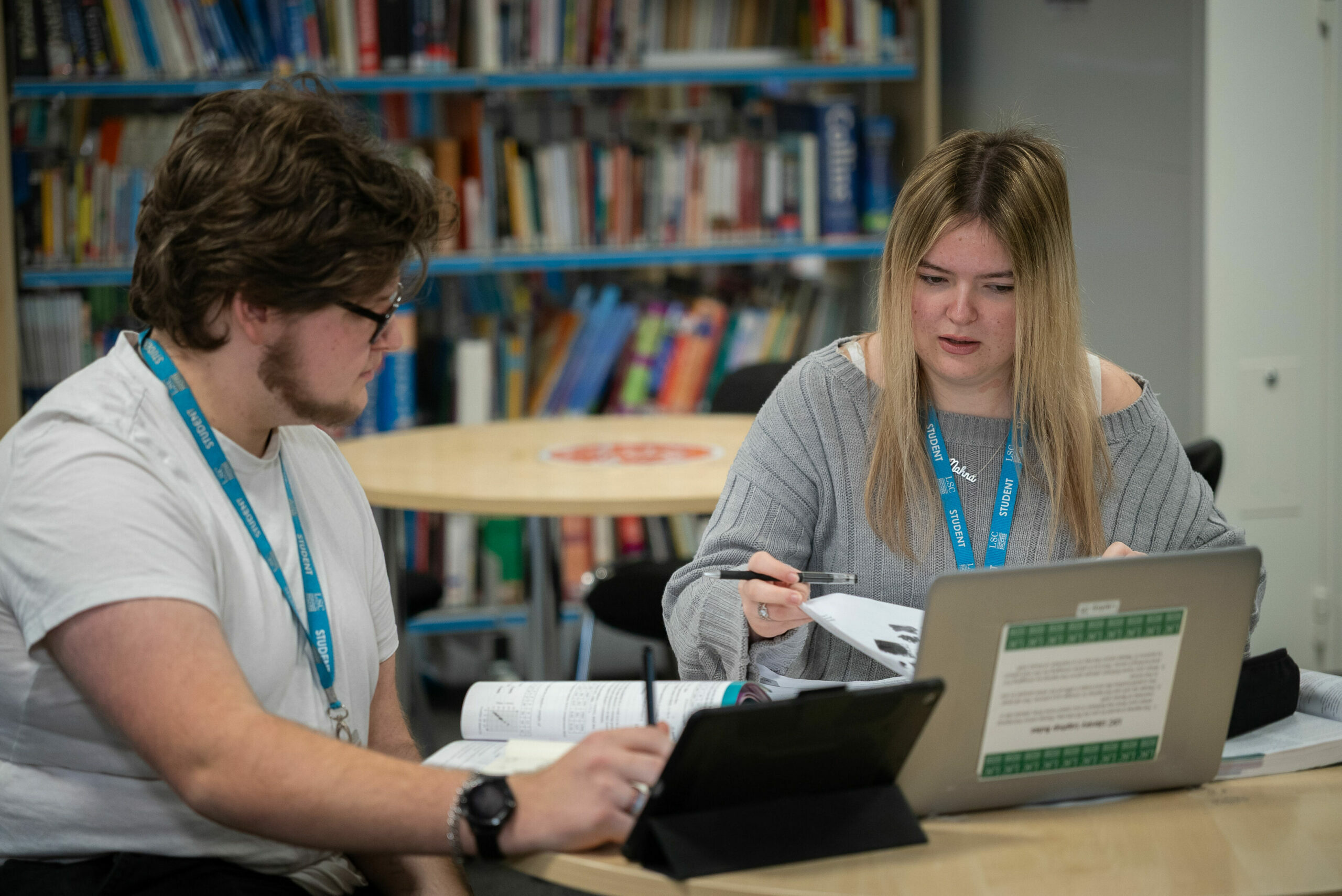 Two students sitting at a table in a library studying together.