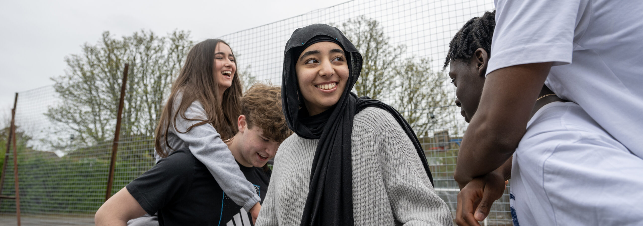 Four young people outside laughing together.
