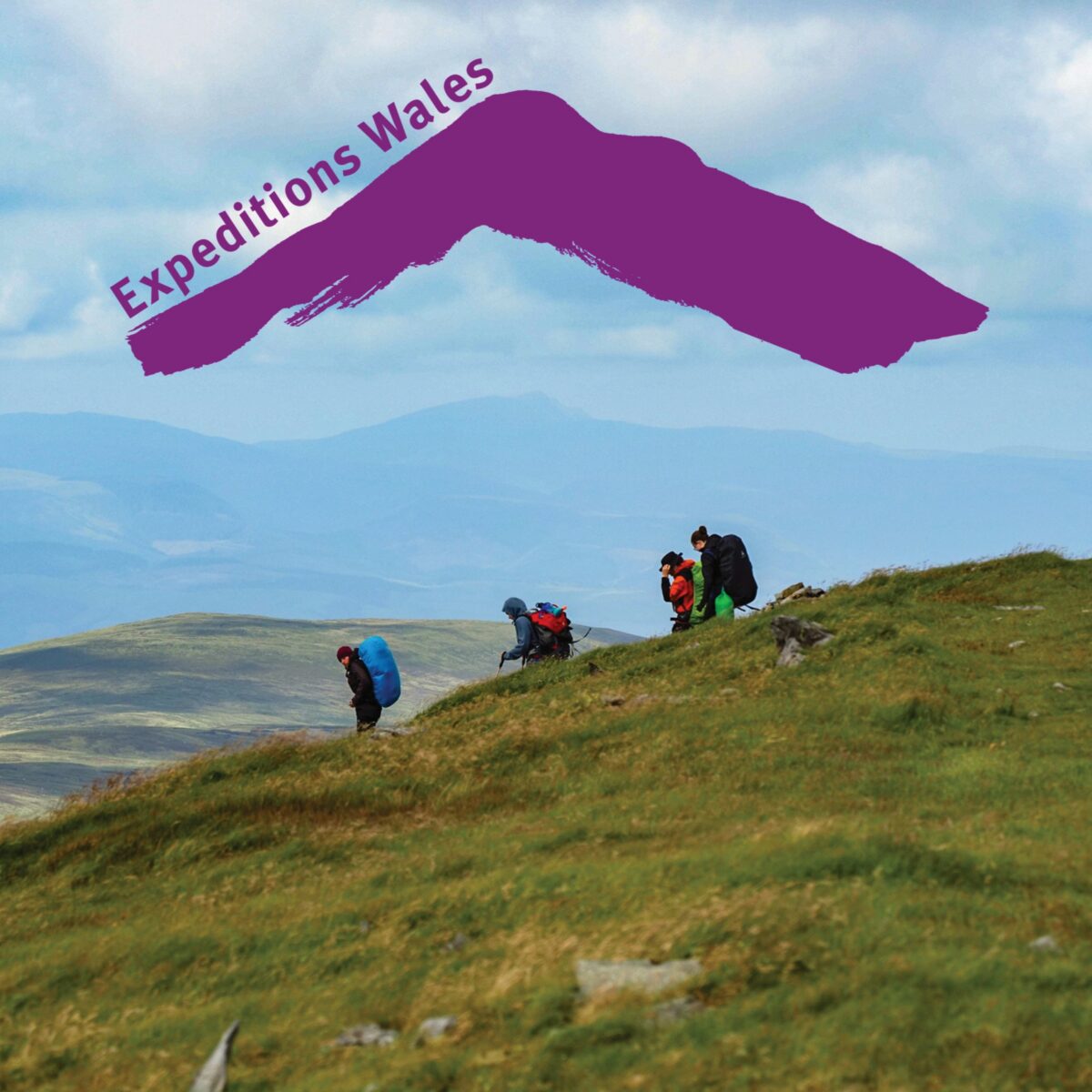 Promotional image for Expeditions Wales featuring a group of hikers carrying large backpacks walking along a grassy mountain ridge. Rolling hills and distant mountains stretch across the background beneath a cloudy sky. At the top of the image, a large purple mountain-shaped graphic contains the text “Expeditions Wales”. The landscape highlights an outdoor adventure and expedition setting in a mountainous environment.