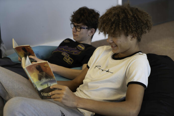 Two young people sitting in a sofa reading books.