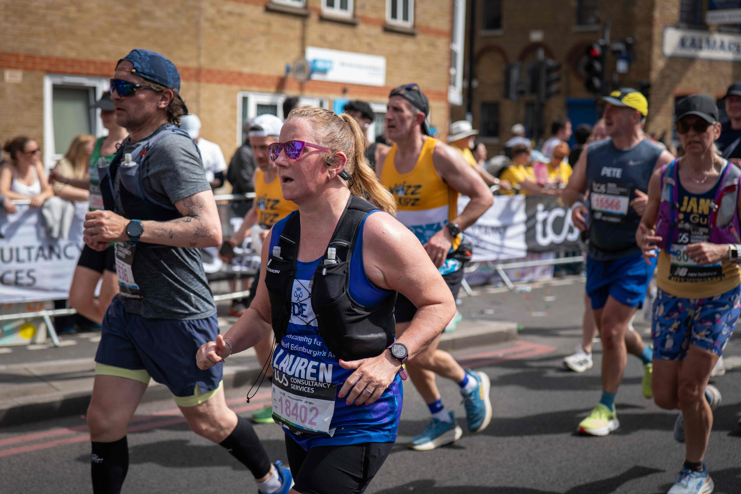 A group of runners in a marathon, one of them is wearing a D of E tank top.