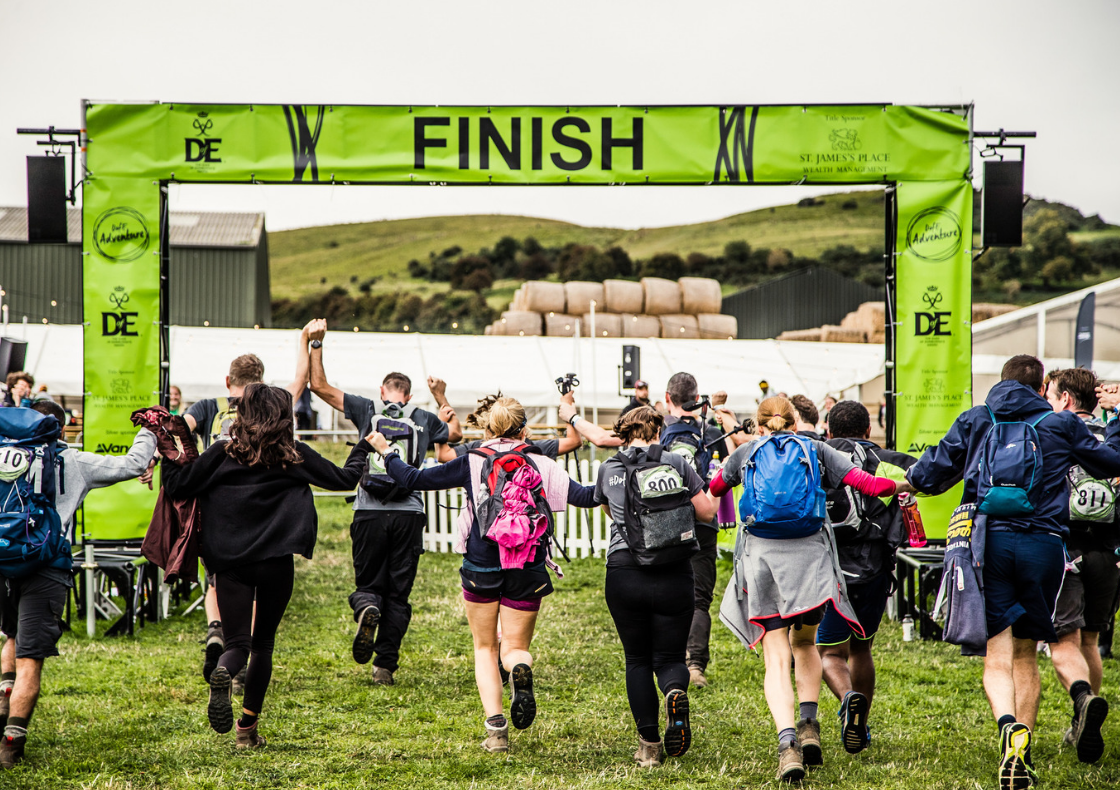 Group with backpacks running towards DofE Adventure finish line