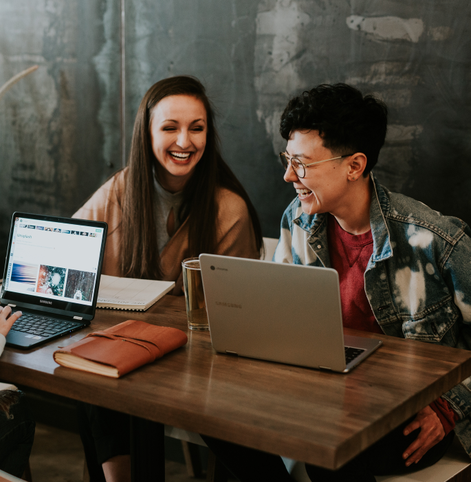 Young woman and man sat in front of laptop laughing