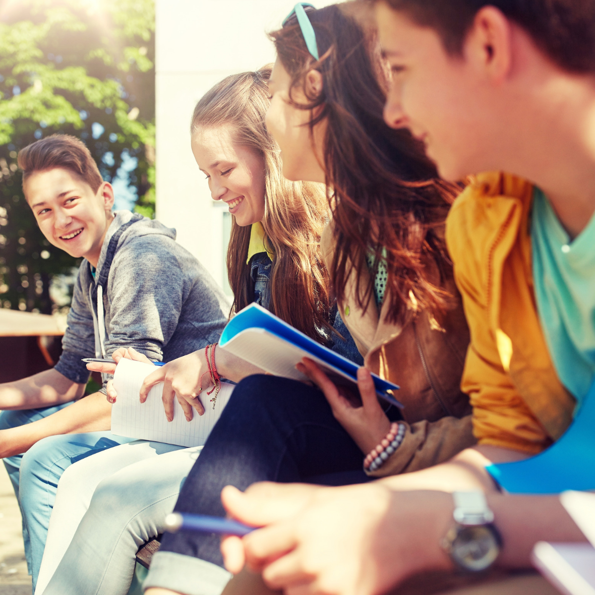 Young people sat down with notebooks talking and laughing
