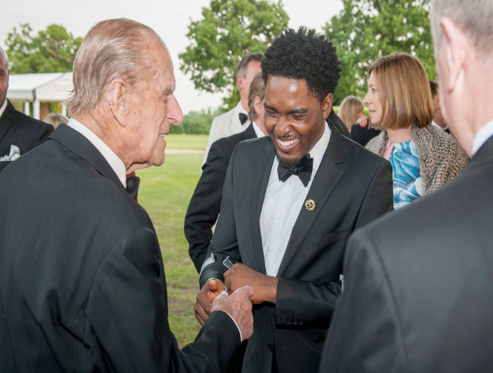 Young man Raphael shaking hands with the Duke of Edinburgh and smiling