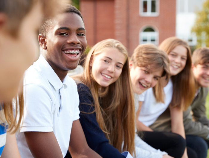 Group of young people sat on a wall smiling and laughing