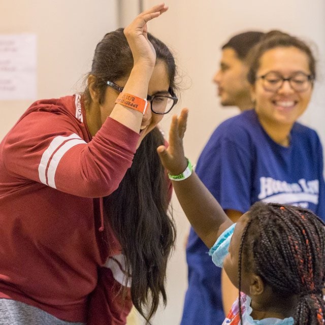 A older girl high fiving a young girl smiling