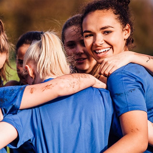 Group of young people who are huddled in circle laughing in a group sports activity