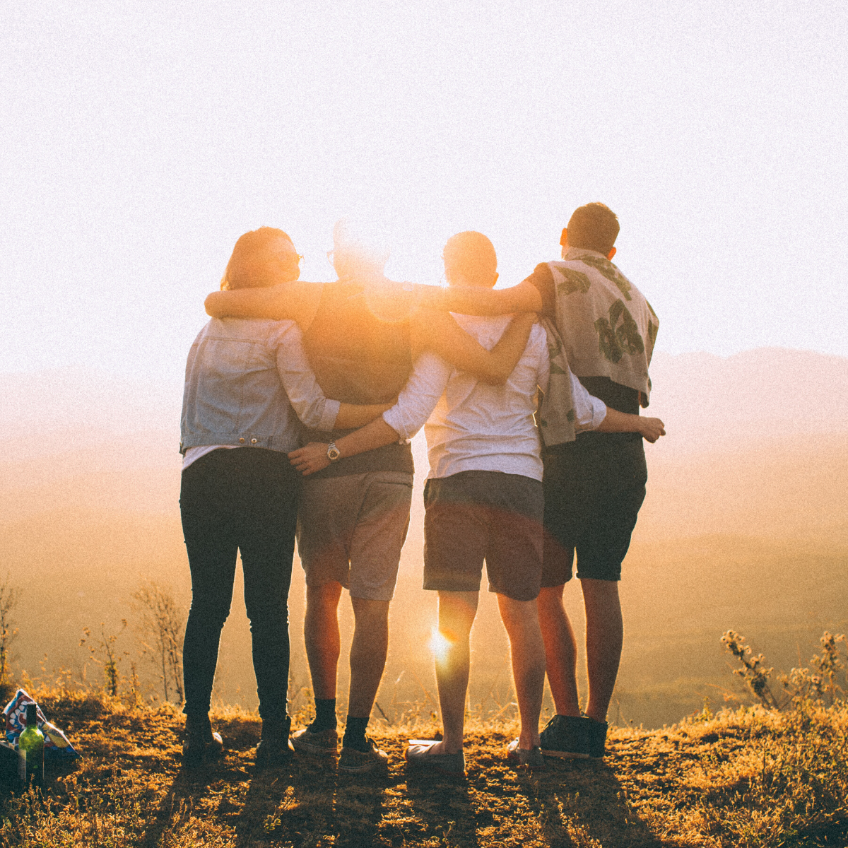 Group of young people hugging at sunset
