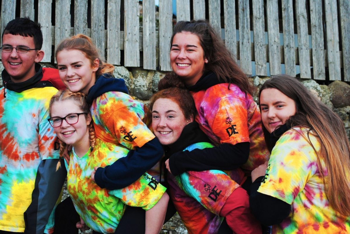 Group of smiling young people in multicoloured tshirts