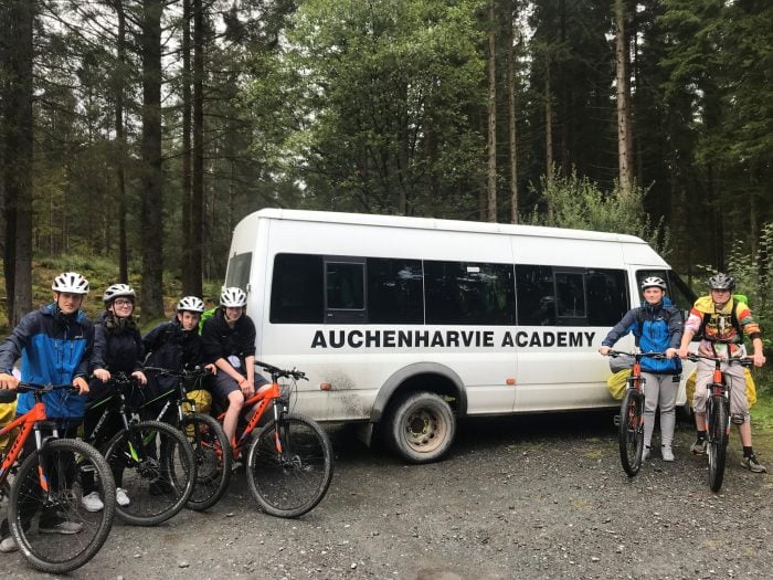 Photo of a white bus with DofE participants on bikes