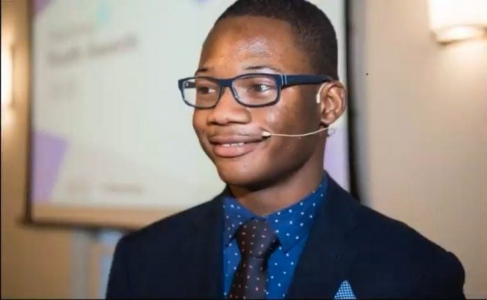 Abdullahi in a suit wearing a microphone at a conference