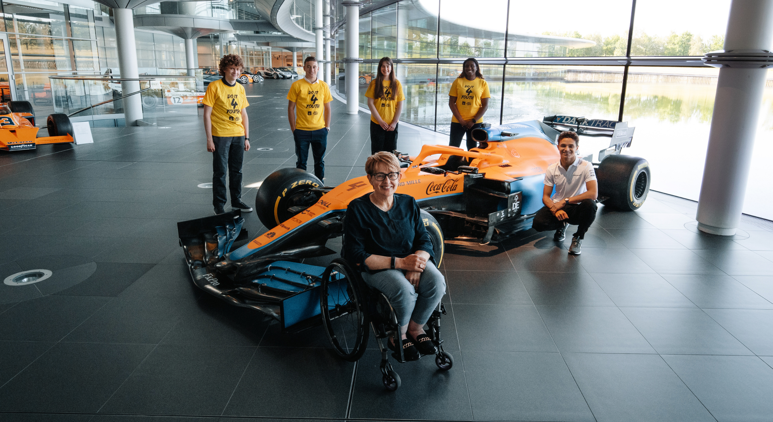 Group of Do It 4 youth participants with lando norris with a McClaren racing car