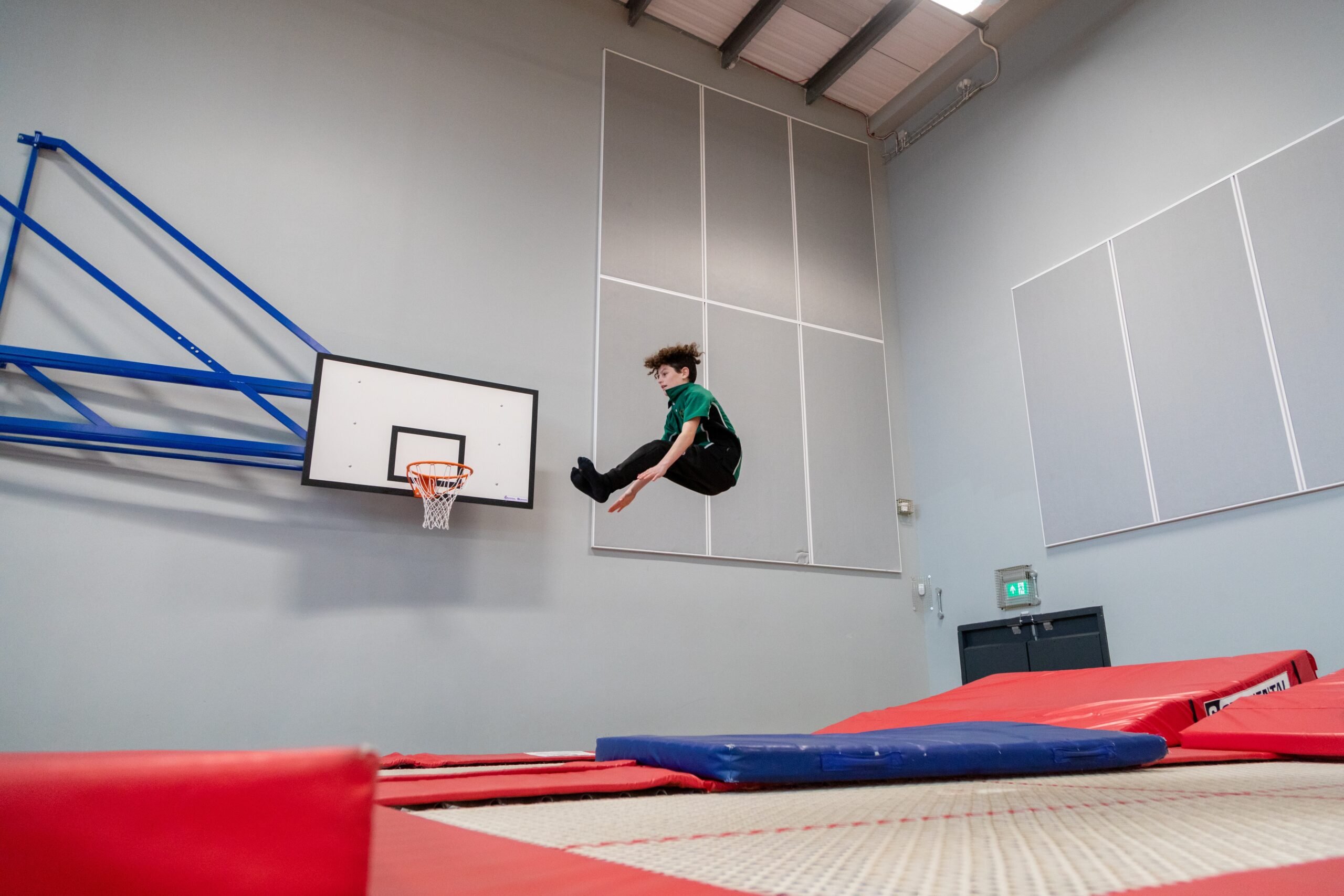 A young person in the air above a trampoline, it looks like they're sitting down in the air.