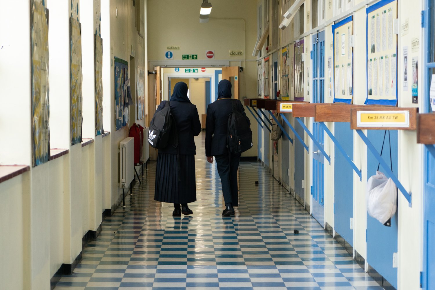 Two girls walking down a school hallway.
