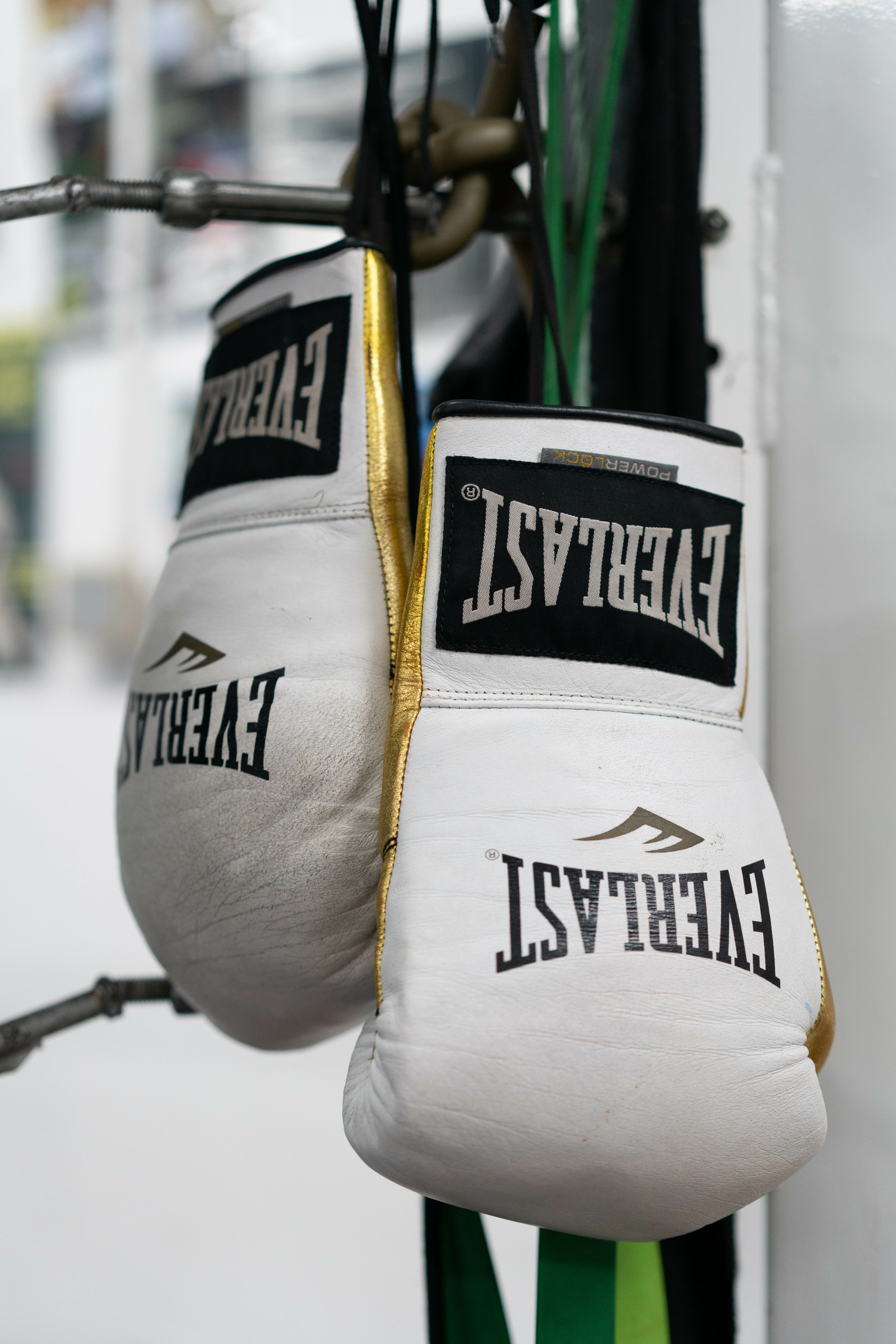 A pair of white boxing gloves hanging on the corner of the boxing ring.