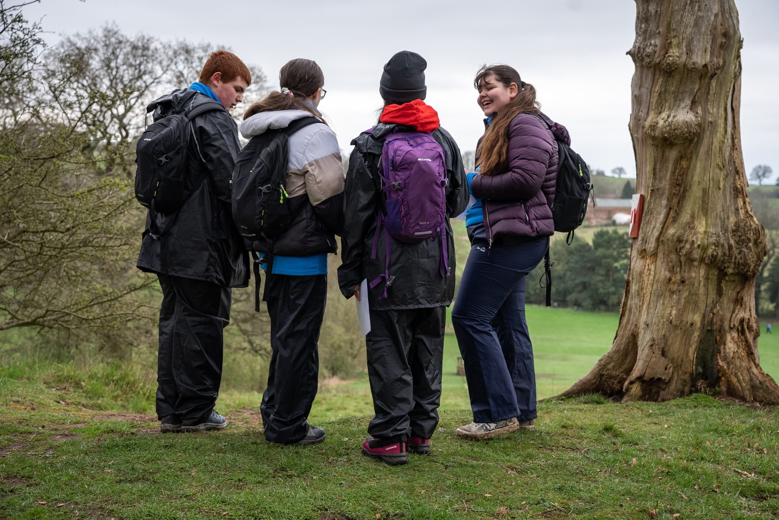 Four young people standing together and talking outside.