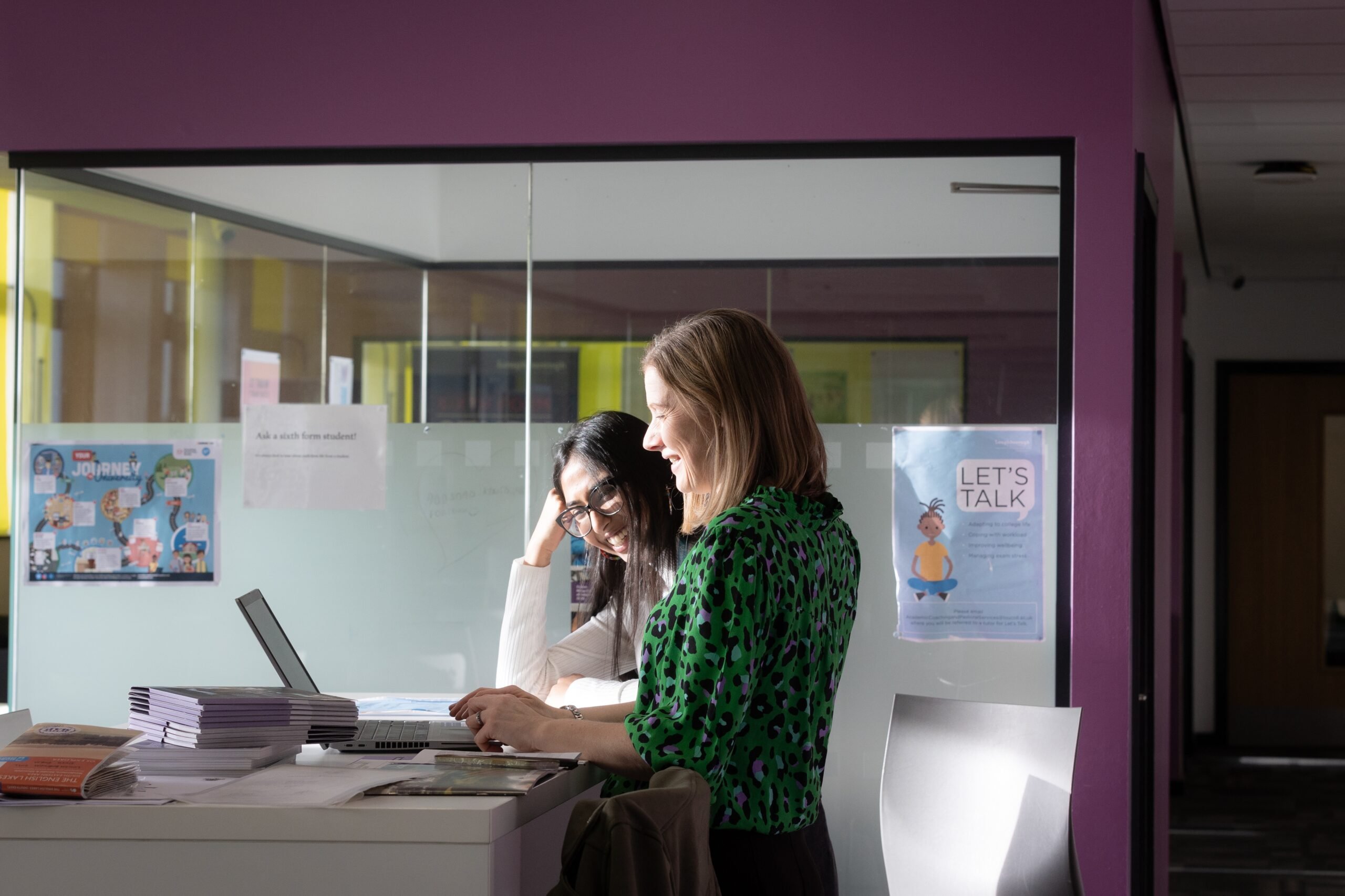 Two people smiling and looking at a laptop.