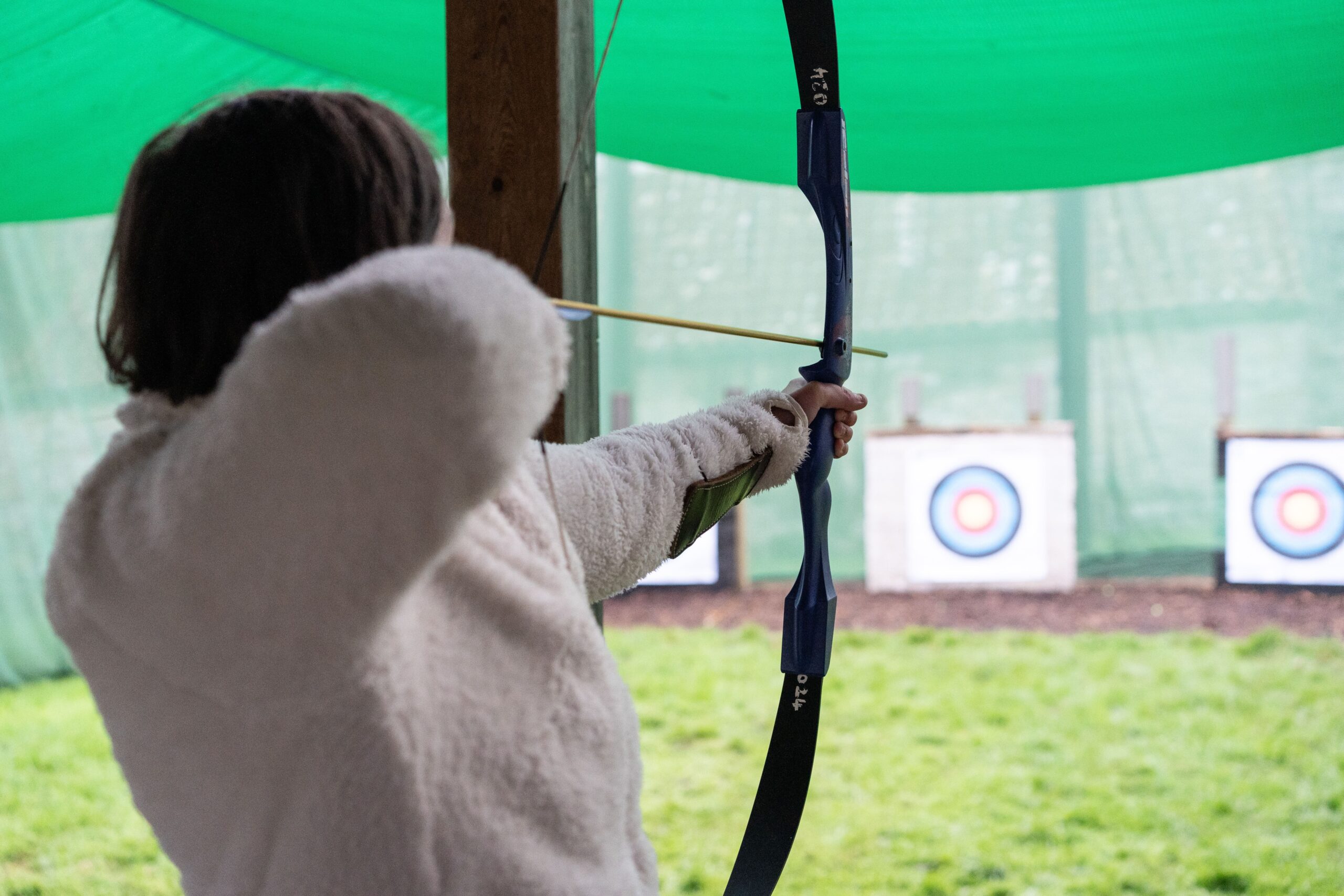 A young person aiming at a target with a bow and arrow.